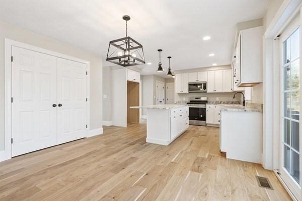 kitchen featuring stainless steel appliances, light wood-style flooring, visible vents, a notable chandelier, and white cabinetry