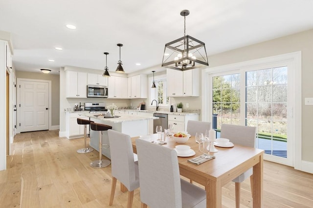 dining room featuring light wood finished floors, baseboards, recessed lighting, and a notable chandelier