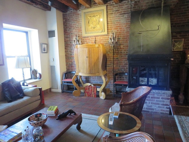 living room featuring beam ceiling, brick wall, and a fireplace