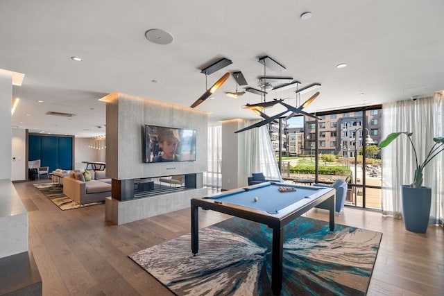 playroom with hardwood / wood-style flooring, pool table, floor to ceiling windows, and a multi sided fireplace