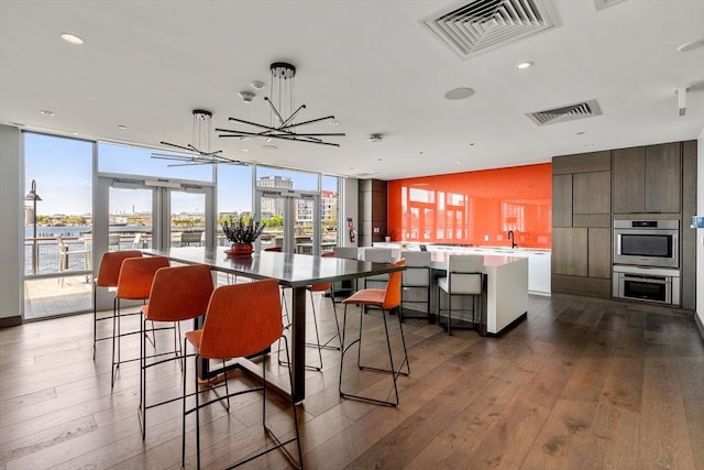 dining area featuring dark hardwood / wood-style flooring, sink, and a wall of windows