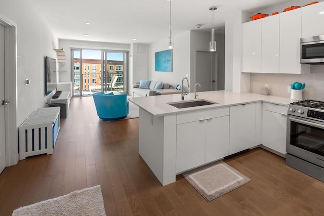 kitchen with sink, white cabinetry, hanging light fixtures, appliances with stainless steel finishes, and kitchen peninsula