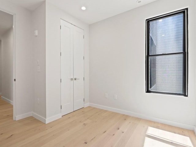 unfurnished bedroom featuring light wood-style flooring, baseboards, a closet, and recessed lighting