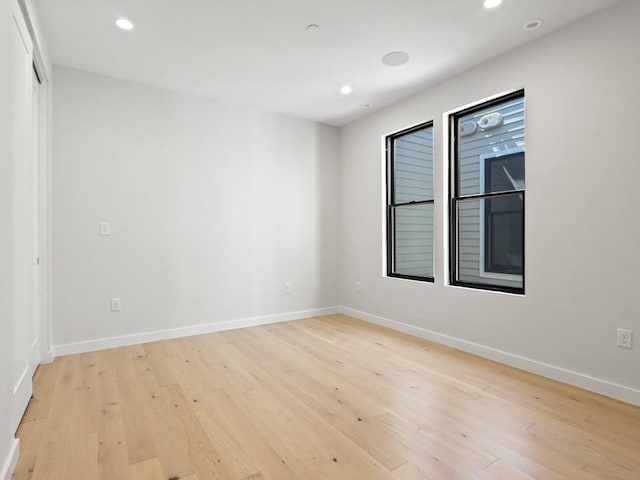 spare room with light wood finished floors, recessed lighting, and baseboards