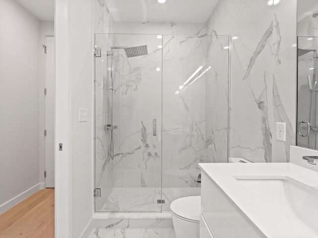 bathroom with toilet, vanity, a marble finish shower, and baseboards