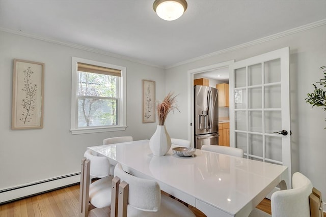 dining space with crown molding, baseboard heating, and light wood-type flooring