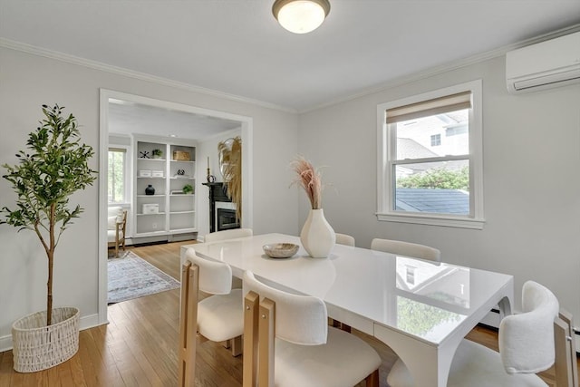 dining space featuring baseboards, ornamental molding, a wall mounted AC, and light wood-type flooring