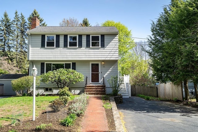 colonial home featuring fence and a chimney