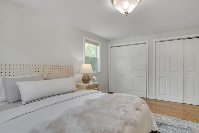 bedroom featuring baseboards, multiple closets, and wood finished floors