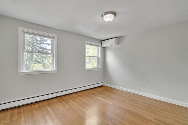 spare room with baseboards, a baseboard radiator, an AC wall unit, and light wood-type flooring