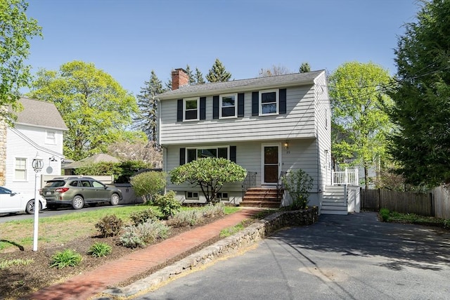 colonial inspired home with fence and a chimney