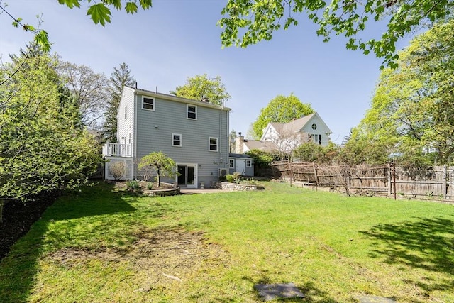 rear view of house with fence and a yard