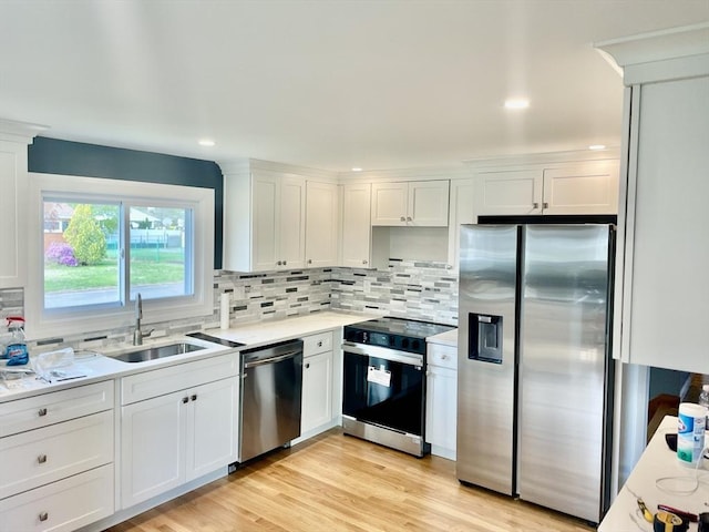 kitchen with a sink, white cabinetry, appliances with stainless steel finishes, and light countertops