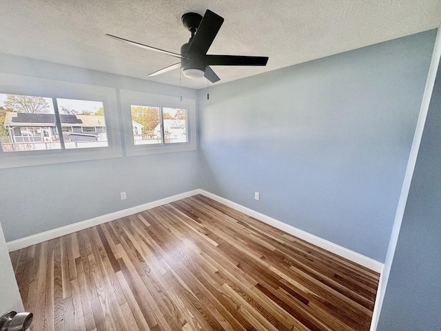 unfurnished room featuring baseboards, a textured ceiling, ceiling fan, and wood finished floors