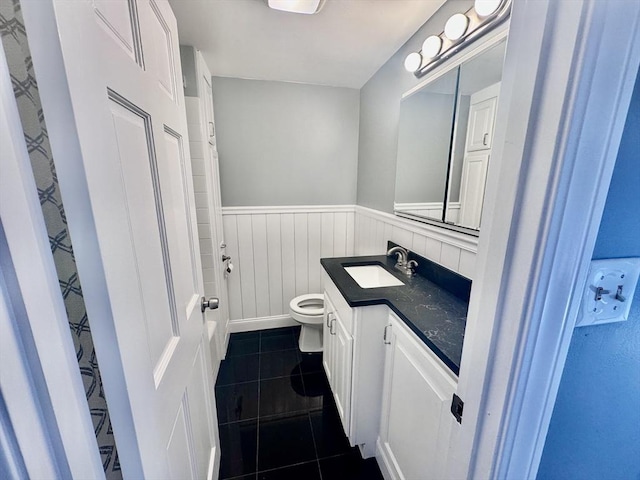 bathroom with vanity, tile patterned flooring, wainscoting, and toilet