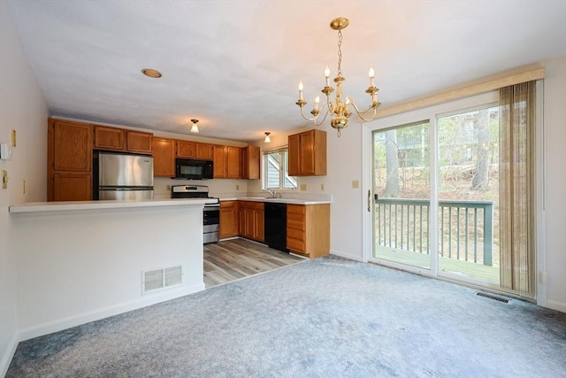 kitchen with visible vents, light colored carpet, light countertops, brown cabinets, and black appliances