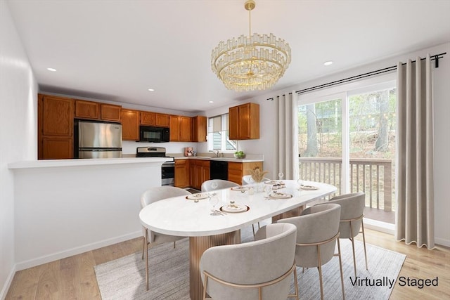 dining space with light wood finished floors, recessed lighting, and an inviting chandelier