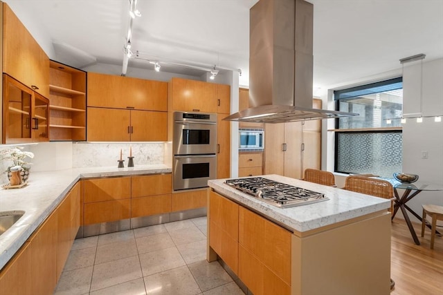 453 Washington St Unit 11E, Boston, MA 02111 - kitchen with island exhaust hood, appliances with stainless steel finishes, tasteful backsplash, open shelves, and a kitchen island