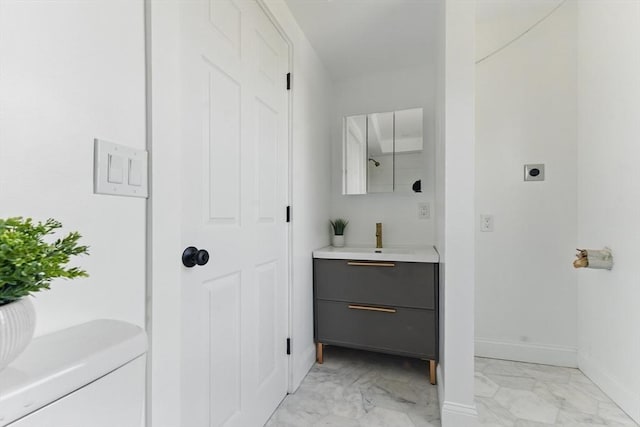 bathroom with marble finish floors, vanity, and baseboards