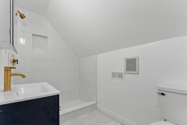 bathroom with lofted ceiling, toilet, a tile shower, marble look tiles, and baseboards