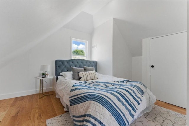 bedroom with lofted ceiling and light wood-type flooring