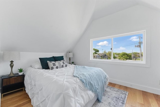bedroom featuring lofted ceiling, wood finished floors, and baseboards