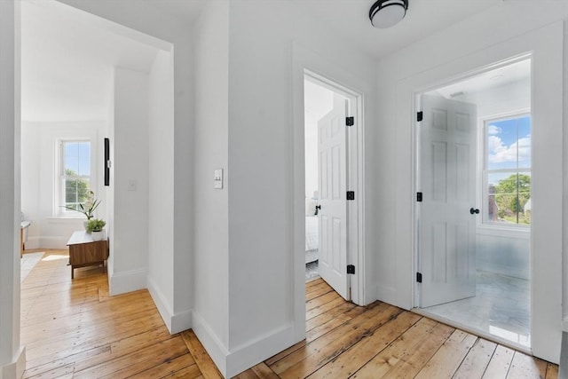corridor with light wood-style flooring and baseboards