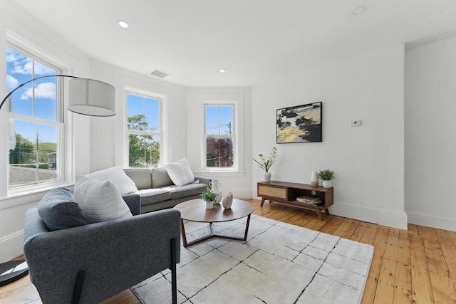 living room featuring baseboards, light wood finished floors, and recessed lighting