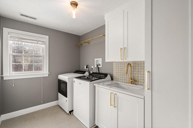 clothes washing area featuring a sink, visible vents, baseboards, cabinet space, and washing machine and clothes dryer