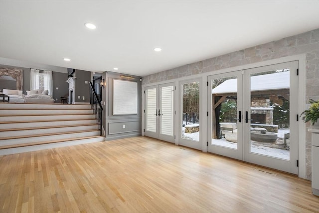 interior space with light wood-type flooring, visible vents, stairway, and french doors