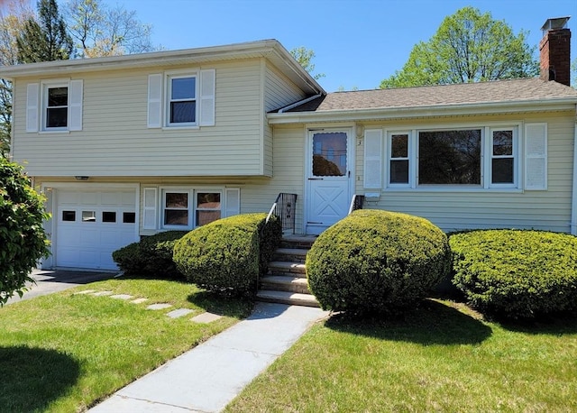 split level home with an attached garage, a chimney, and a front yard