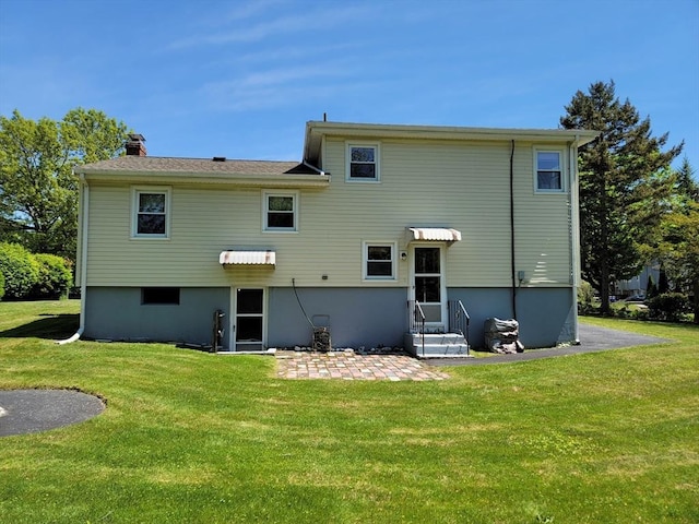 rear view of house featuring a lawn, a patio, and a chimney