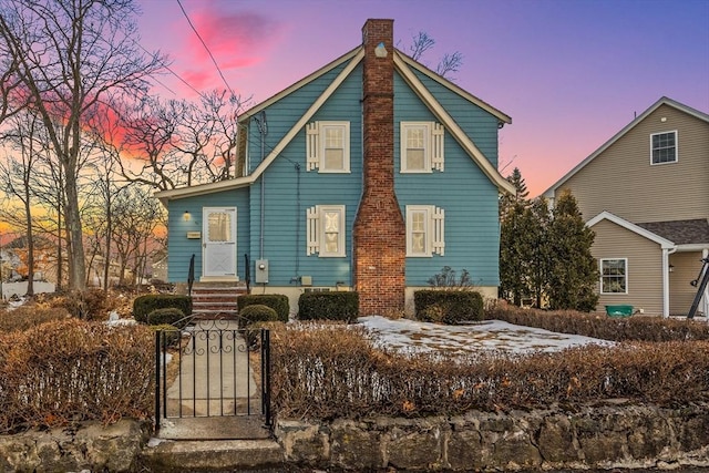 view of front of property featuring a chimney, a fenced front yard, and a gate