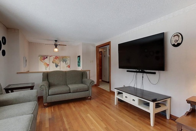 living area with ceiling fan, light wood finished floors, and a textured ceiling