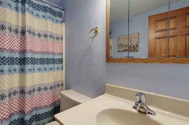 bathroom with a shower with curtain, a textured ceiling, vanity, and toilet