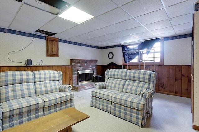 carpeted living area featuring wainscoting, a fireplace, wallpapered walls, and a paneled ceiling