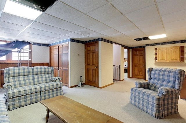 living room with a drop ceiling and light colored carpet