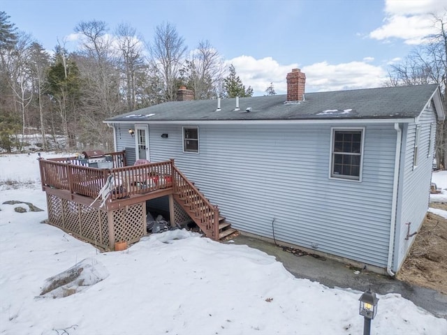 snow covered house featuring a wooden deck and stairway