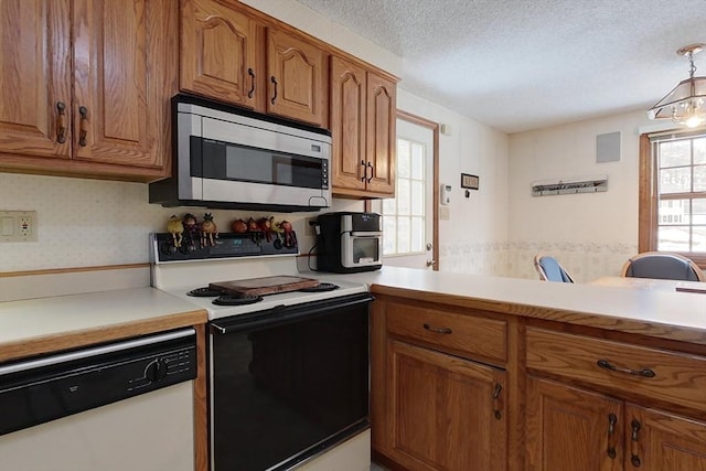 kitchen with stainless steel microwave, electric range oven, white dishwasher, brown cabinetry, and a textured ceiling