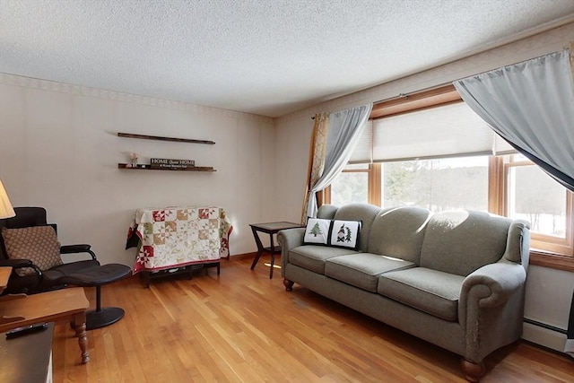 living area featuring a baseboard heating unit, wood finished floors, and a textured ceiling