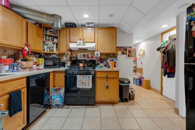 kitchen with a paneled ceiling, light tile patterned floors, and black appliances