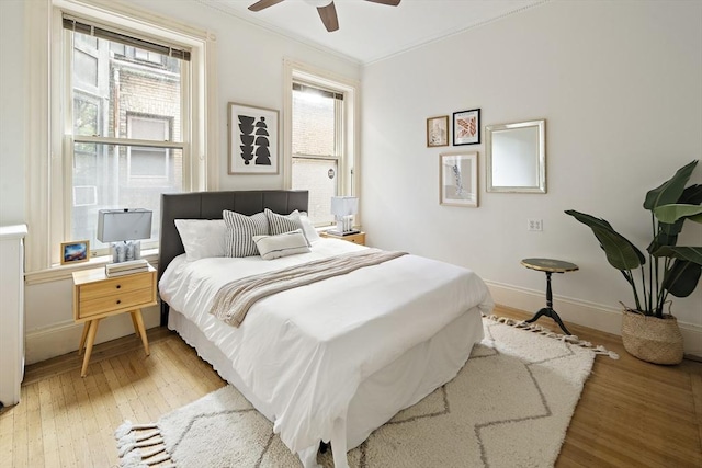 bedroom featuring multiple windows, hardwood / wood-style flooring, ceiling fan, and ornamental molding