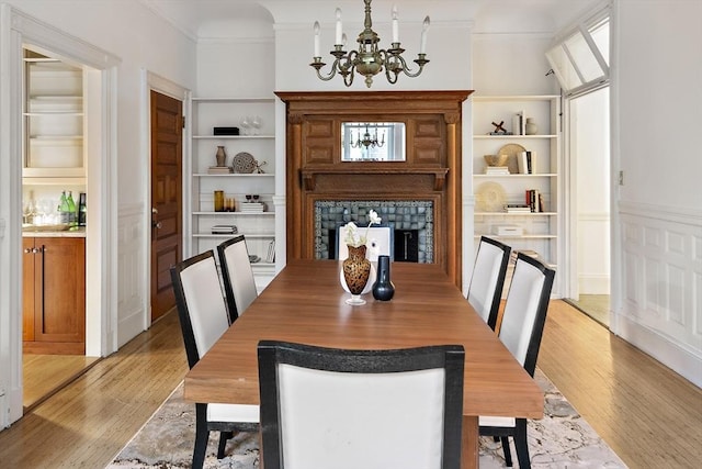 dining area with built in features, light hardwood / wood-style flooring, and a chandelier