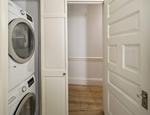 washroom with hardwood / wood-style floors and stacked washer / drying machine