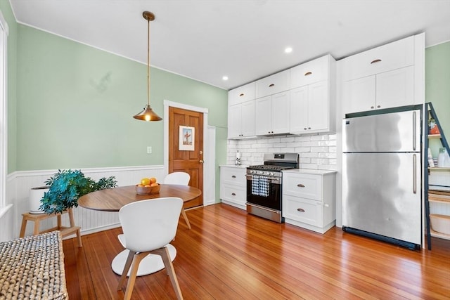 kitchen featuring appliances with stainless steel finishes, white cabinets, and decorative light fixtures