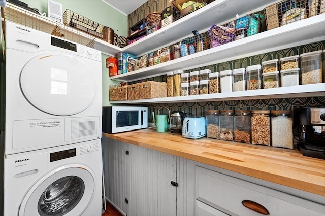 clothes washing area featuring stacked washer / drying machine and laundry area