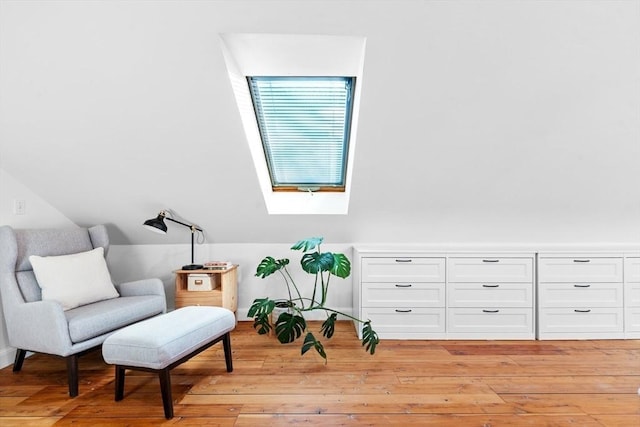 living area featuring vaulted ceiling with skylight and light wood-style flooring