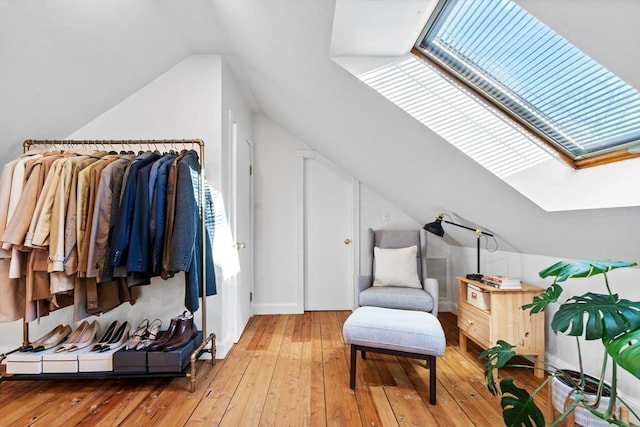 living area featuring light wood finished floors and lofted ceiling with skylight