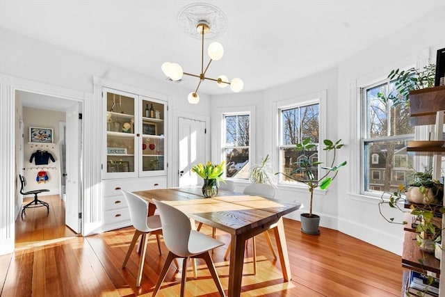 dining space featuring a chandelier, baseboards, and light wood-style floors