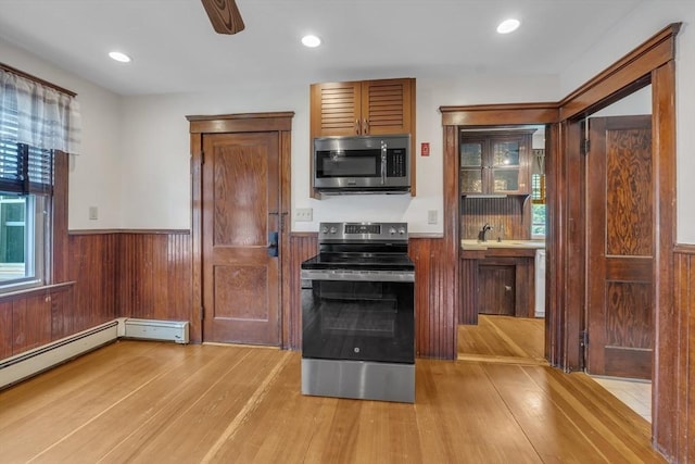 259 Main St, Blackstone, MA 01504 - kitchen with stainless steel appliances, wainscoting, light wood-style flooring, a ceiling fan, and wooden walls